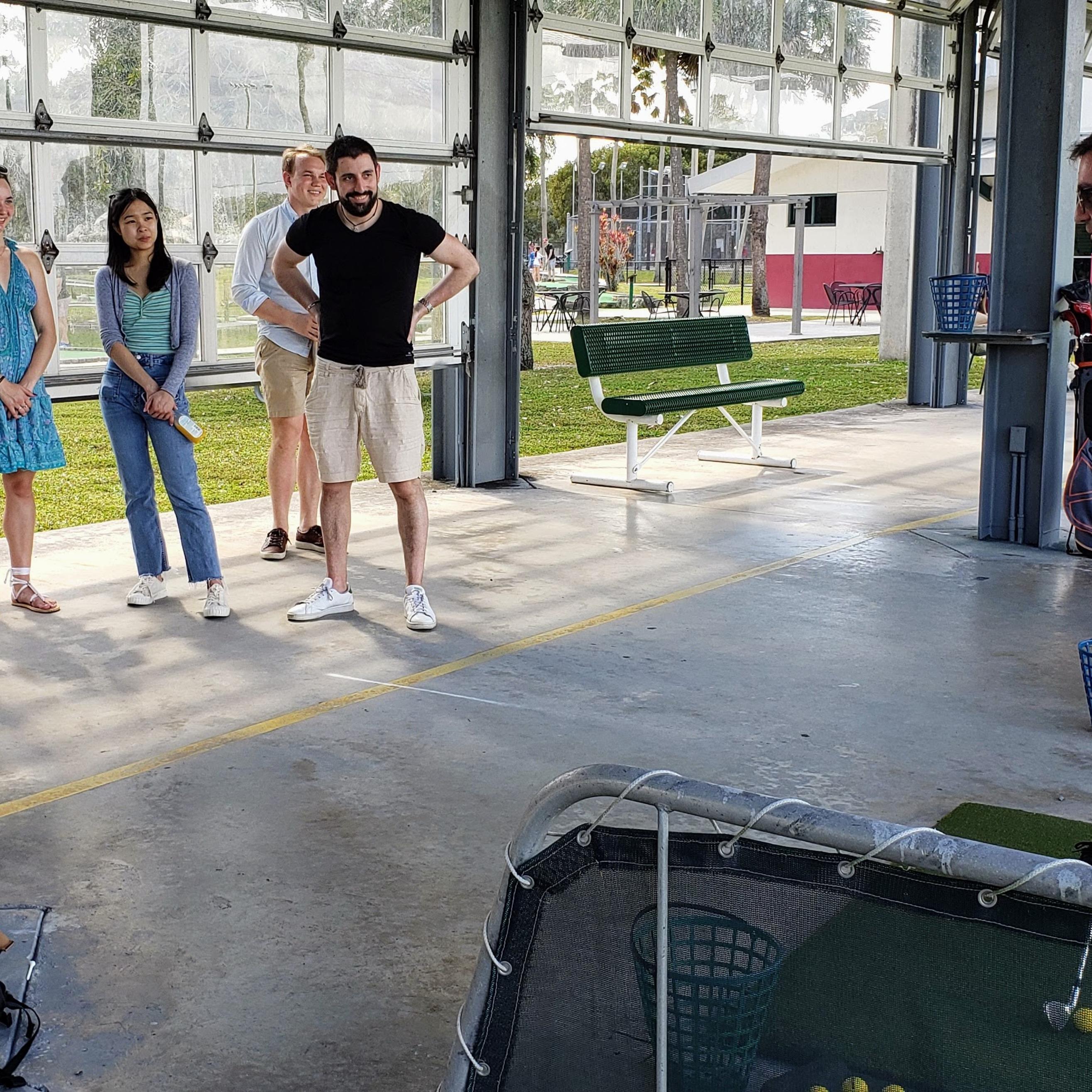 Will teaches the group how to golf at a driving range